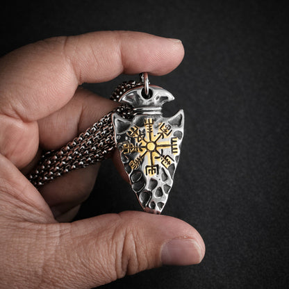 Hand holding a  pendant with intricate designs against a dark background