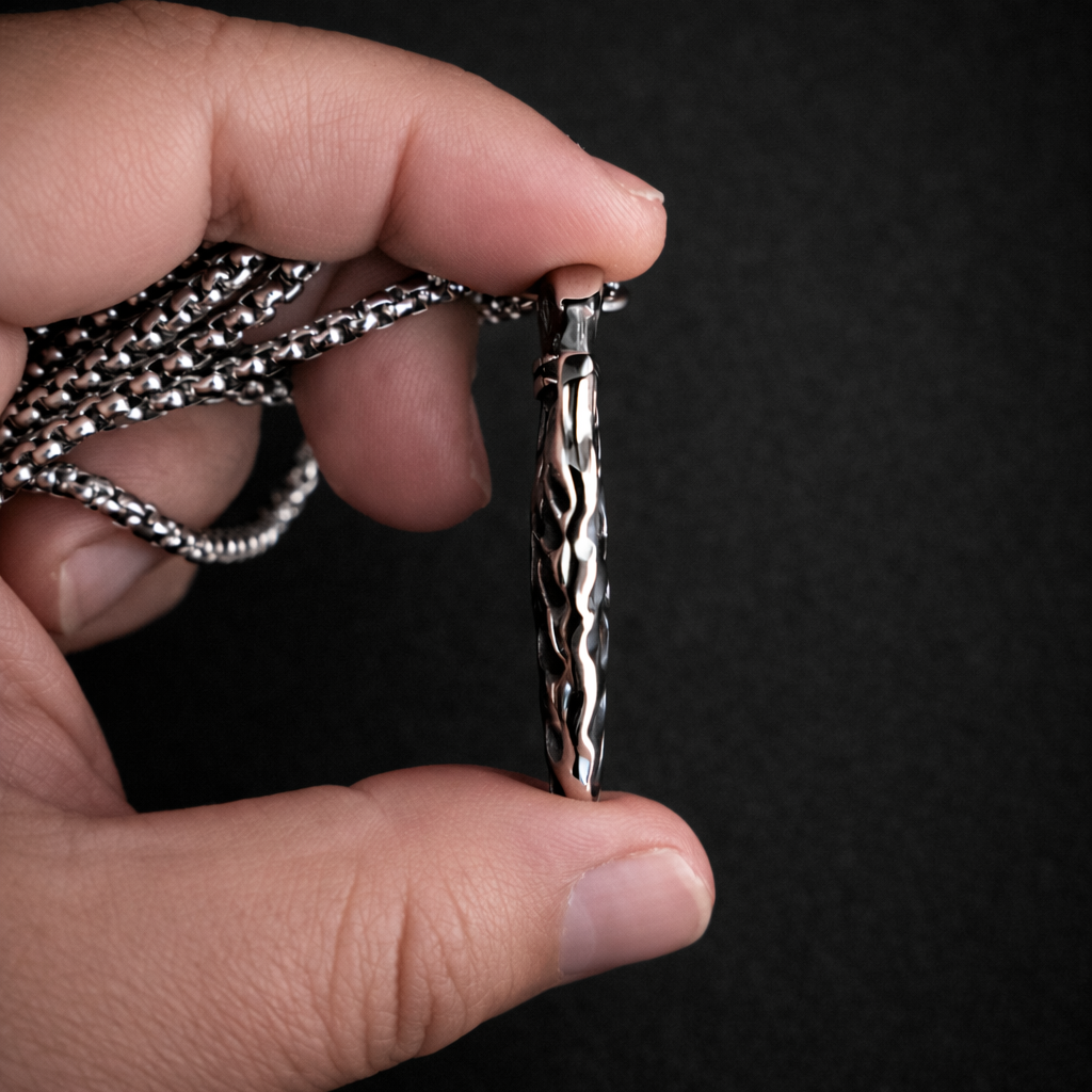 Hand holding a silver chain against a black background